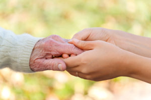 Senior and young holding hands over green and brown leaves background